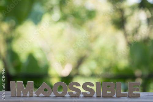 The letters word IMPOSSIBLE in motivation meaning of impossible make it possible concept. On wood background.