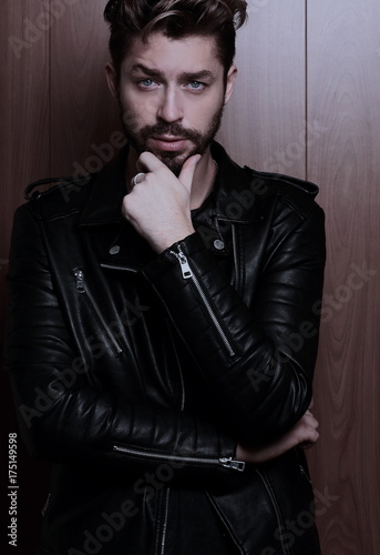 Portrait of young handsome fashionable man against wooden wall.