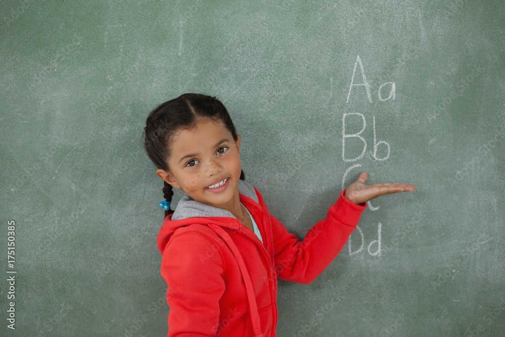 Young girl gesturing over chalk board