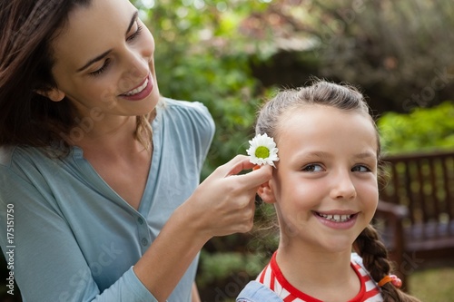 Smiling mother positioning white flower in hair of girl © wavebreak3