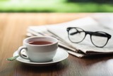 Newspaper reading glasses coffee cup.