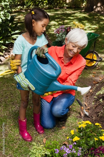 Smiling grandmother and girl watering plants