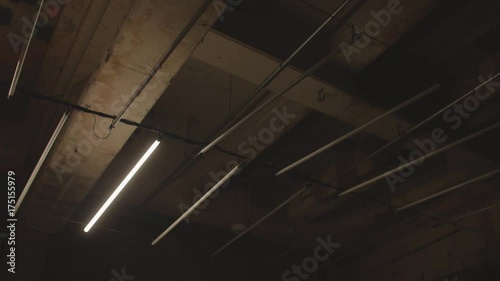 4k shot of white fluorescent lighting turn on and off and in industrial building. Many neon lights blinking and flashing on the ceiling.