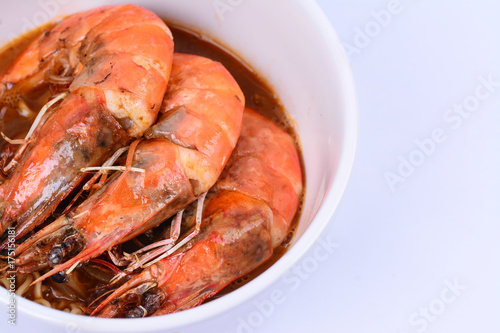 Close up view of prawns on curry noodles in a white ceramic bowl. White background.