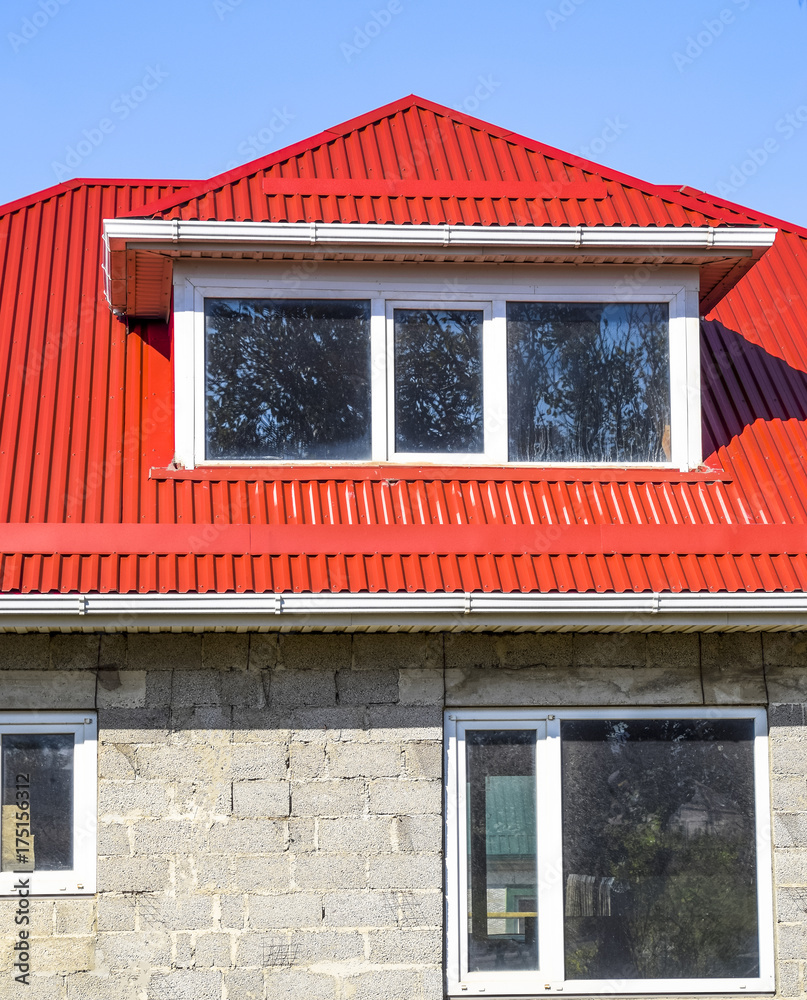 Naklejka premium House of cinder block. House with plastic windows and a red roof of corrugated sheet