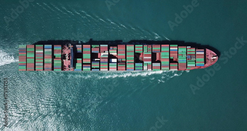 Huge large mega container ship sails on open water fully loaded with containers and cargo - aerial view