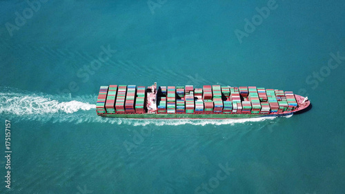 Huge large mega container ship sails on open water fully loaded with containers and cargo - aerial view
