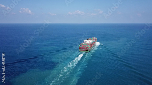 Huge large mega container ship sails on open water fully loaded with containers and cargo - aerial view