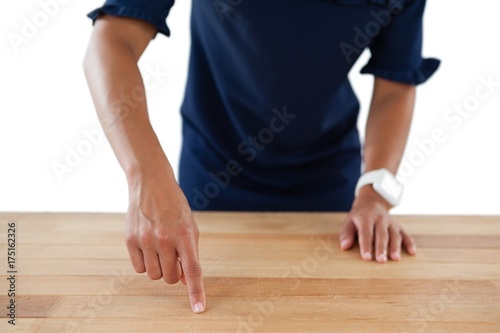 Businesswoman touching invisible screen on wooden table