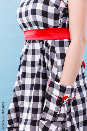 Woman in checked dress holding hand in pocket