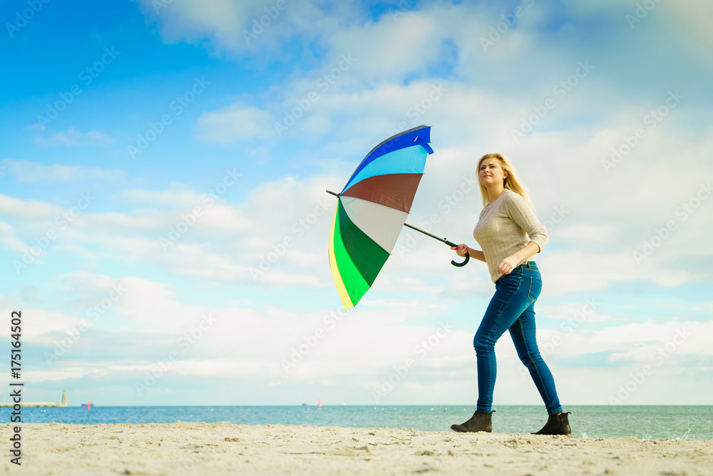 Woman holding colorful umbrella on beach