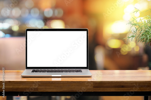 Laptop blank screen on wooden table in coffee shop morning sunshine background photo