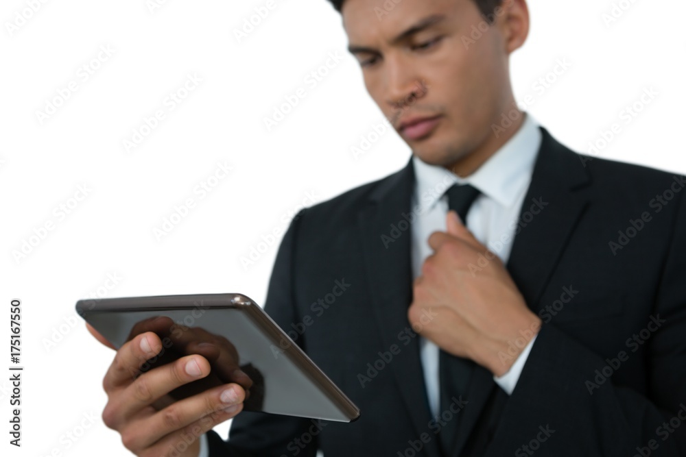 Businessman holding necktie while using tablet computer Businessman holding necktie while using tablet computer