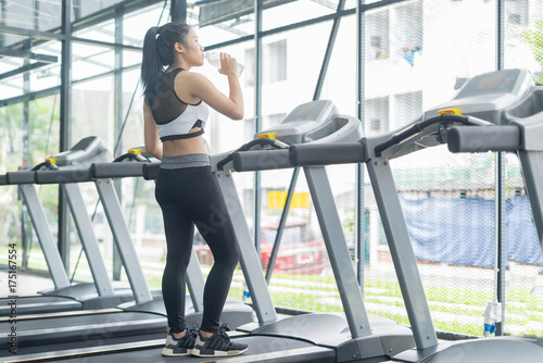 Fitness woman in training drinking water after exercises in gym