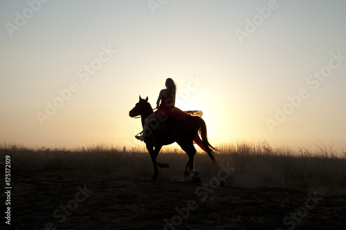 Horse riding. Silhouette girl on sunset background