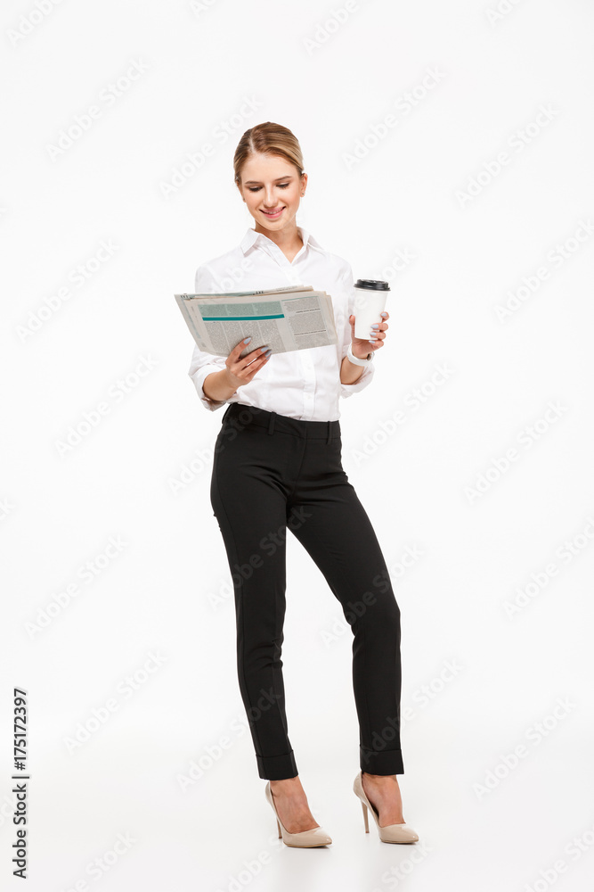 Full length image of Cheerful blonde business woman reading newspaper Full length image of Cheerful blonde business woman reading newspaper