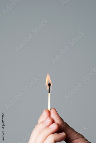 hand holding a burning matchstick