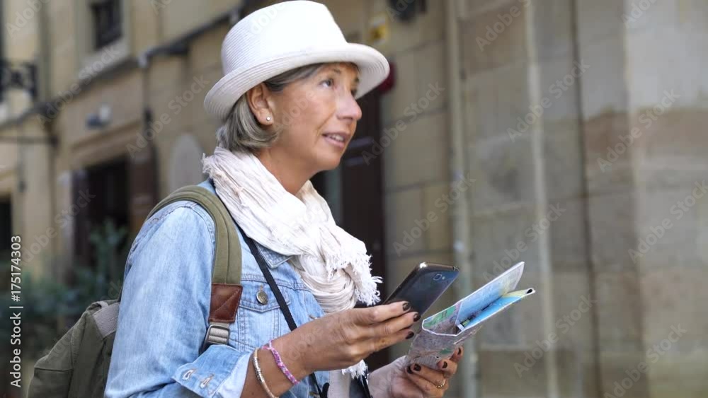 Senior woman visiting Spanish city, using smartphone and map Senior woman visiting Spanish city, using smartphone and map