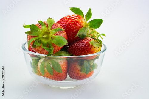 Strawberries in glass bowl against white background.