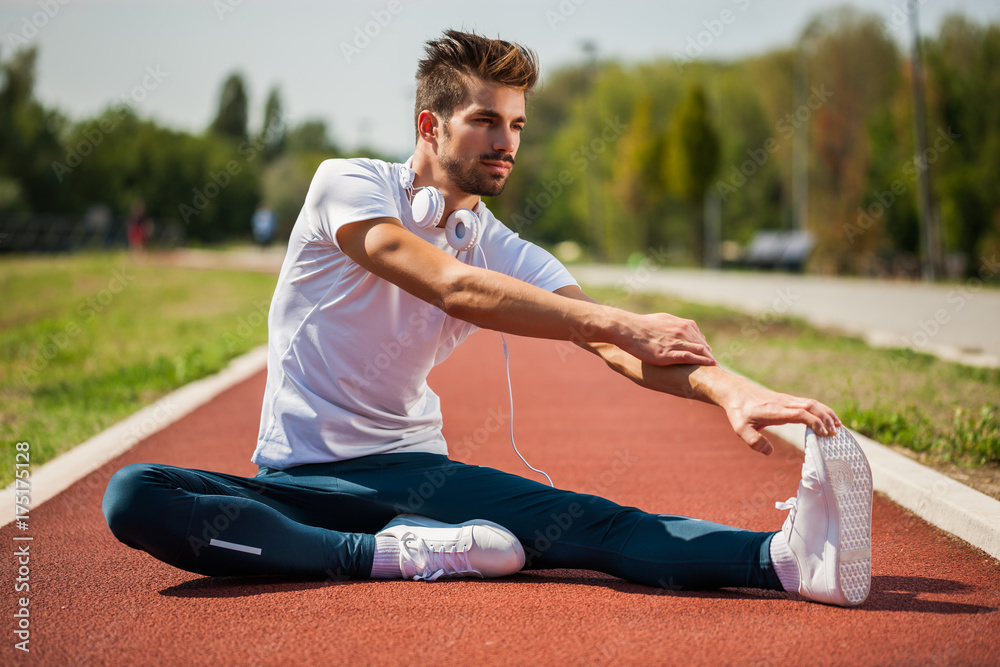 Young man is exercising on sunny day. He is stretching his body. Young man is exercising on sunny day. He is stretching his body.