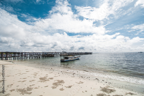 Traditional Fishing Boat and Traditional Wooden Dock at Tropical Beach  photo