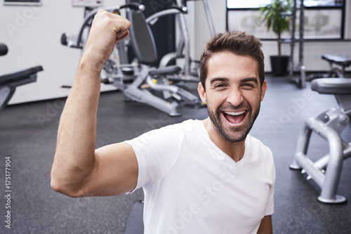 Success athlete punching air in gym, portrait