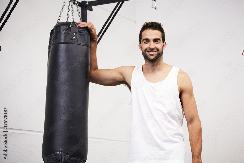 Boxer dude with punch bag in gym, portrait