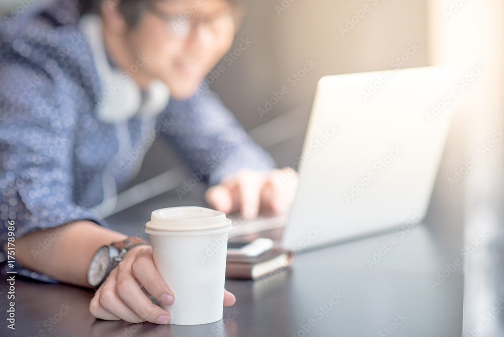 Young Asian man working with his laptop computer and holding coffee cup in library. high school or university college student, educational concept Young Asian man working with his laptop computer and holding coffee cup in library. high school or university college student, educational concept