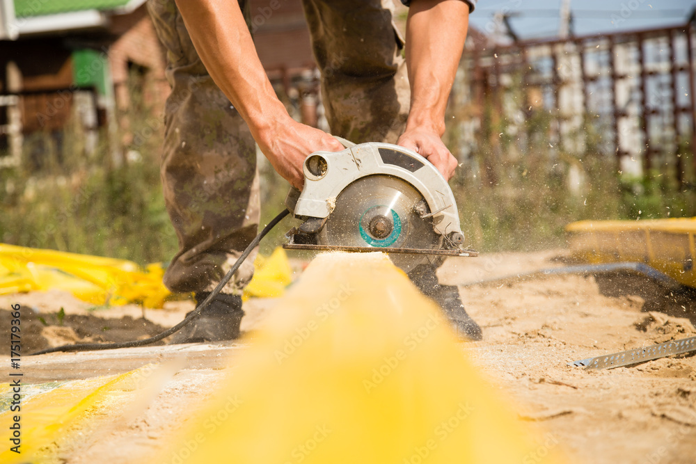 worker saws a wooden plank at a construction site worker saws a wooden plank at a construction site