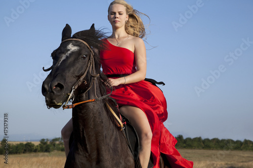 Young woman galloping on horse. Blonde in fluttering dress