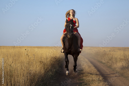 Horseback riding. Young woman jumps on stallion fast