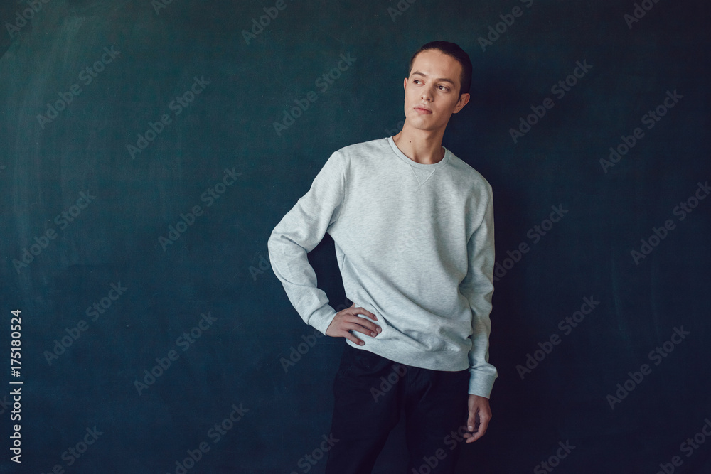 Young man in gray sweatshirt on black background. Mock-up.