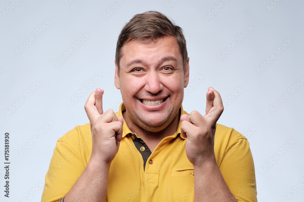 Attractive fat man in yellow t-shirt waiting for special moment and crossing fingers. Attractive fat man in yellow t-shirt waiting for special moment and crossing fingers.