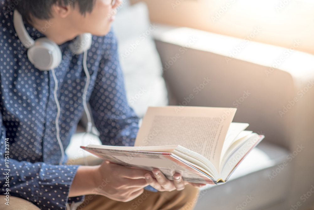 Young Asian man university student reading book on sofa in library, education research and self learning in university life concepts Young Asian man university student reading book on sofa in library, education research and self learning in university life concepts