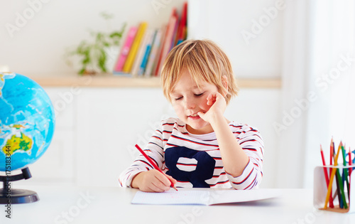 young kid, boy doing homework at home photo