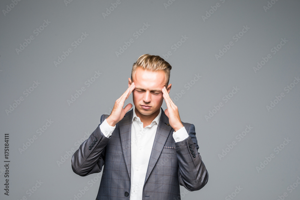 Sad man in gray suit touching his temples because of suffering from migraine on gray background Sad man in gray suit touching his temples because of suffering from migraine on gray background