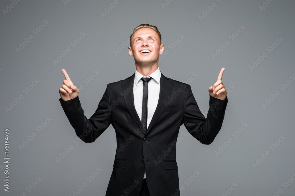 Portrait of business man pointing fingers up isolated on the gray background Portrait of business man pointing fingers up isolated on the gray background