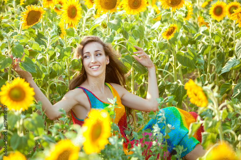 Happy and lovely woman sits in a field among yellow sunflowers. Happy and lovely woman sits in a field among yellow sunflowers.