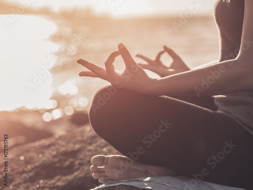 Yoga concept. Closeup woman hand practicing lotus pose on the beach at sunset