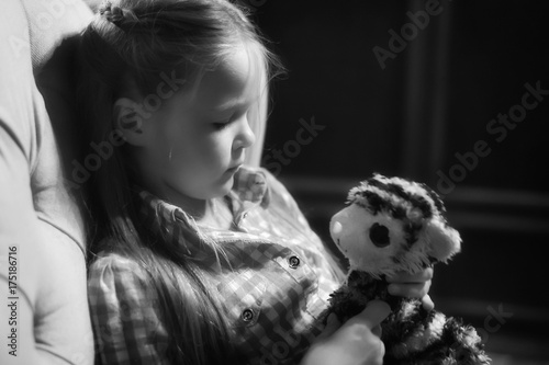 sad little girl holding toy with her hands