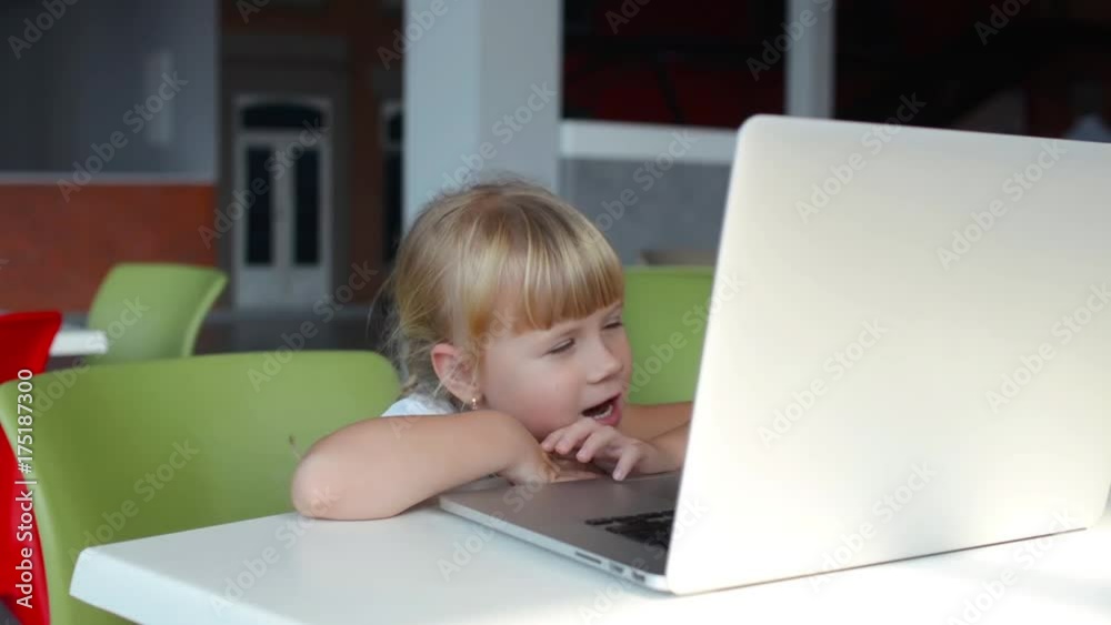 5 year old little girl watching cartoons on the laptop in cafe 5 year old little girl watching cartoons on the laptop in cafe