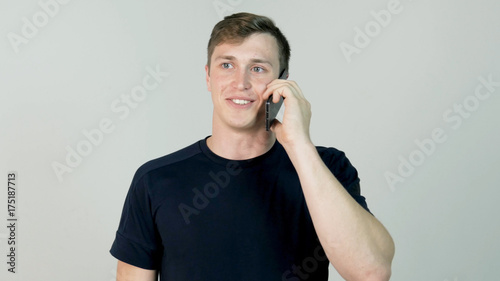 Happy smiling young man talking on mobile isolated on white background photo