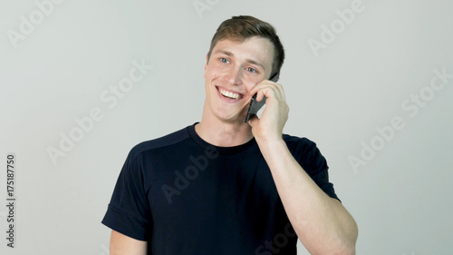 Happy smiling young man talking on mobile isolated on white background photo