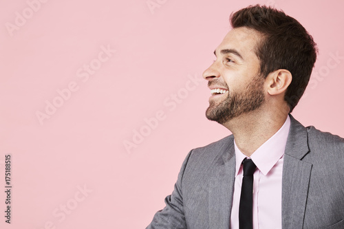 Laughing business guy in profile in pink studio
