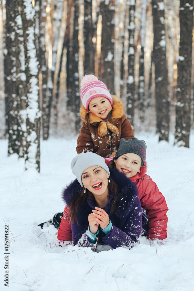 Young mother with two daughters playing in the snow outdoors
