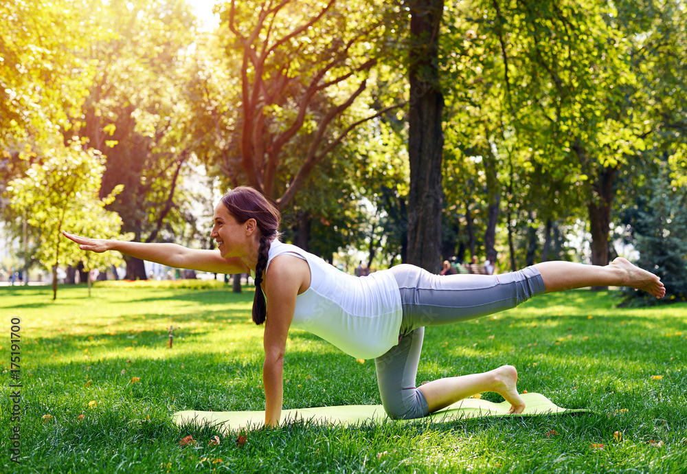 Pregnant woman practicing yoga posture on yoga mat Pregnant woman practicing yoga posture on yoga mat