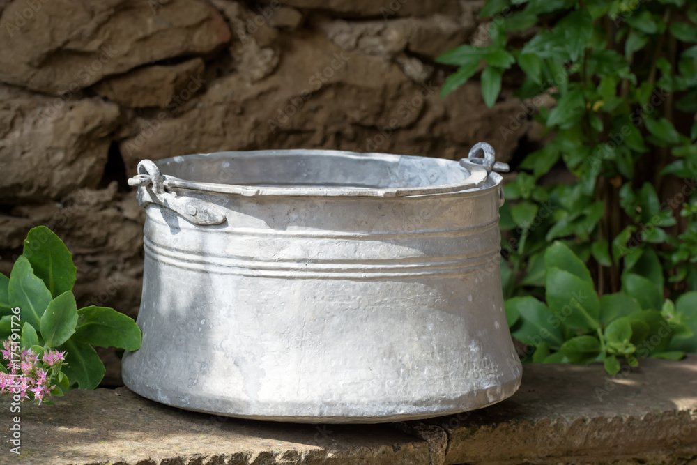 Old metal water container in the garden- traditional Bulgarian copper water container (bakir). Used to bring water from the well. Old metal water container in the garden- traditional Bulgarian copper water container (bakir). Used to bring water from the well.