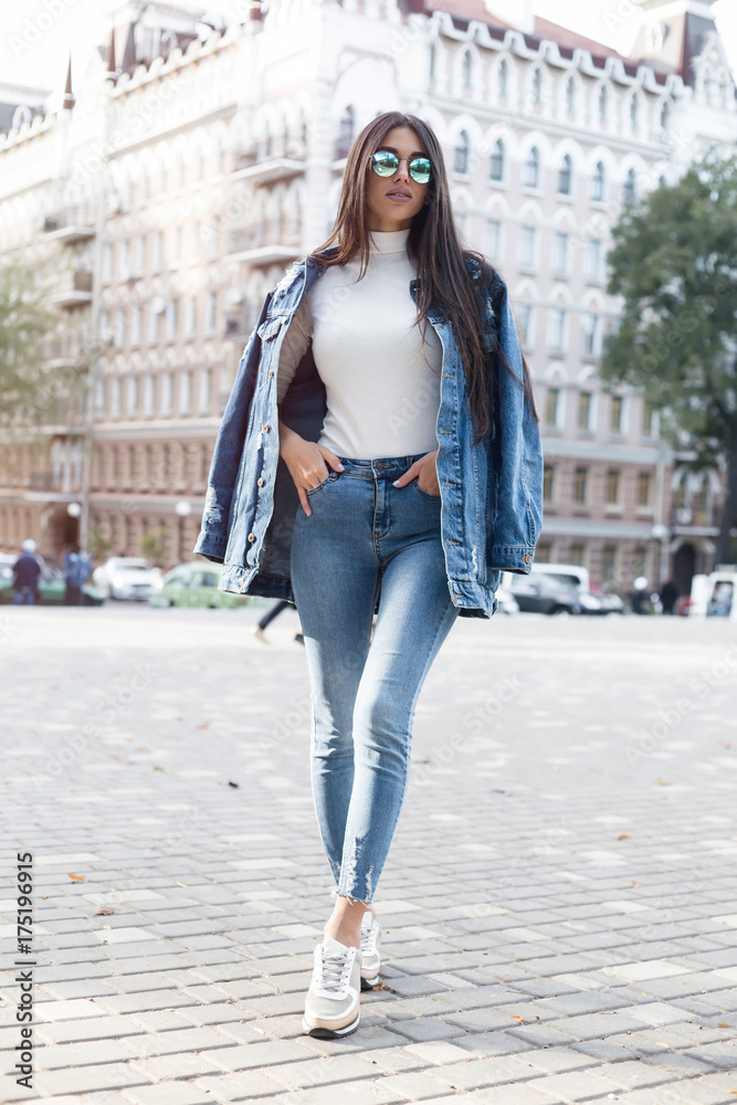 Hipster girl wearing blank gray t-shirt, jeans and backpack posing against  rough street wall, minimalist urban clothing style.Stylish happy young  woman wearing boyfriend jeans and long jeans coat Stock Photo | Adobe