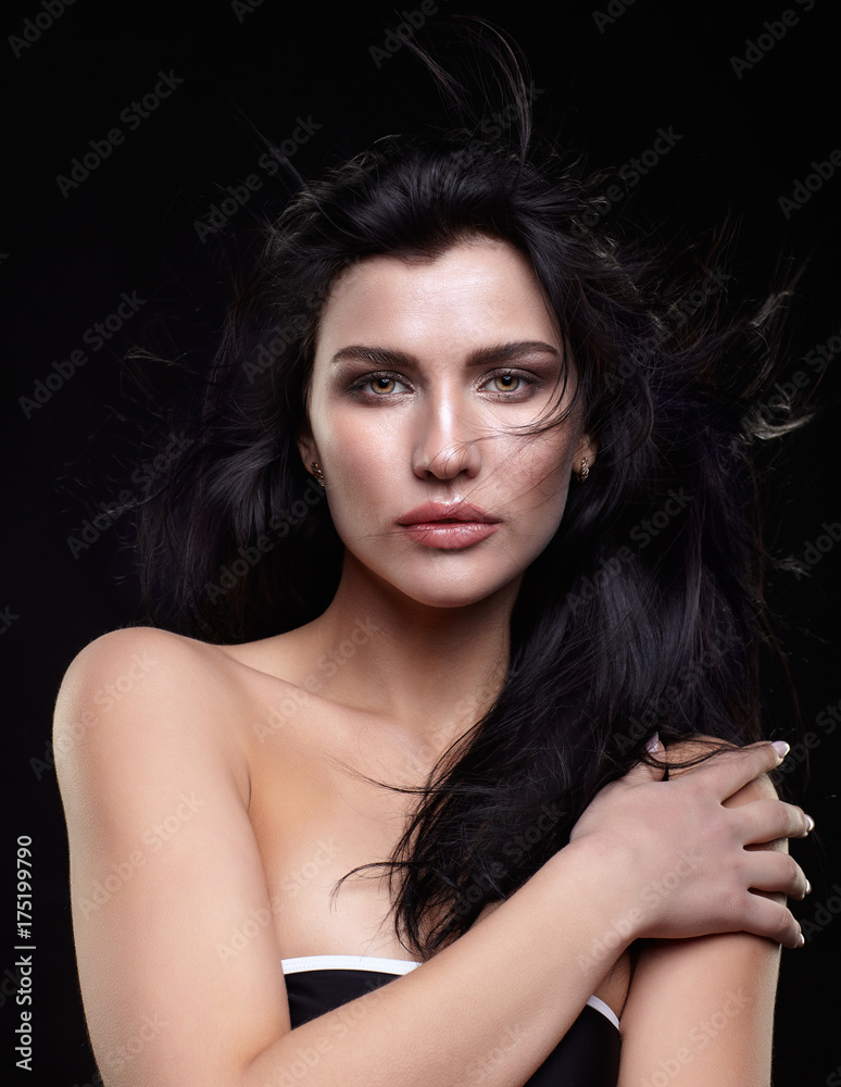 Portrait of a young brunette woman with long black streaming hair on black Portrait of a young brunette woman with long black streaming hair on black