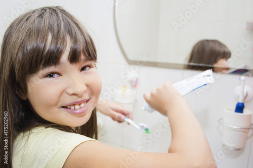 A kid girl brushing her teeth on a bath room